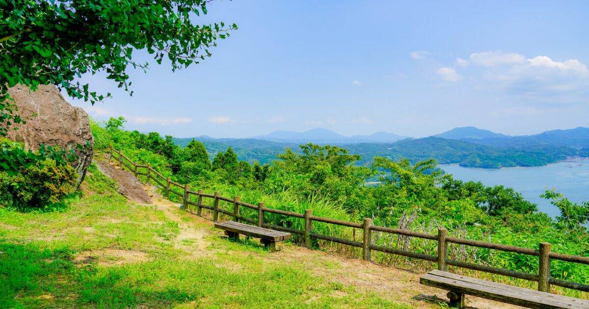 山頂のベンチから望む緑豊かな海と島々の風景