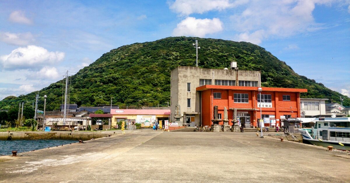 山を背景にした呼子港と赤い建物のある港町の風景